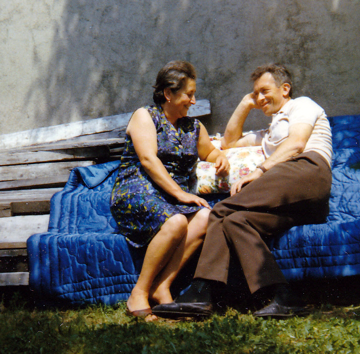 Grands-parents assis sur un canapé de jardin et qui se sourient