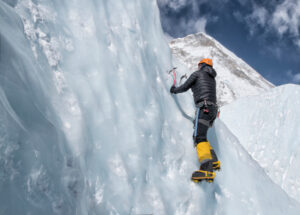 Homme alpiniste qui gravit une montagne du Népal avec un piolet.