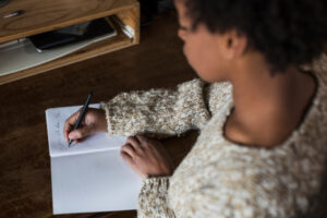Jeune femme écrivant dans un cahier à son bureau.