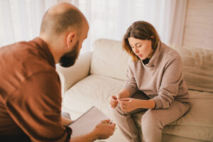 Jeune femme déprimée en consultation avec un psychologue qui prend des notes.
