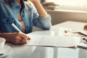 Jeune femme qui écrit une lettre fictive.