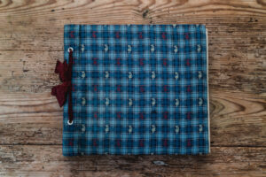 Joli carnet de voyage avec des motifs bleus et rouges posé sur du bois.