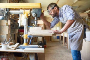 Menuisier qui se sert d'une machine à couper le bois dans son atelier.