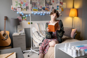 Jeune fille malade qui lit un livre assise sur son lit d'hôpital.