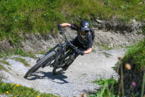Jeune femme avec un casque qui fait du vtt de descente sur un chemin.