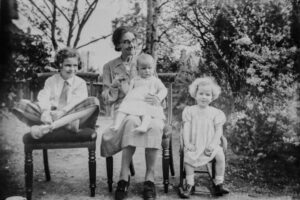 Photo ancienne en noir et blanc représentant une mère avec ses trois enfants dont un bébé.