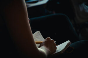 Jeune femme qui écrit dans un cahier.