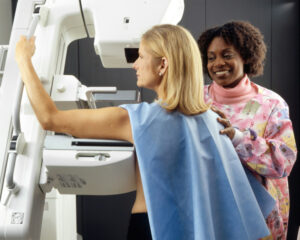 Femme blonde portant une blouse bleue et faisant une mammographie.